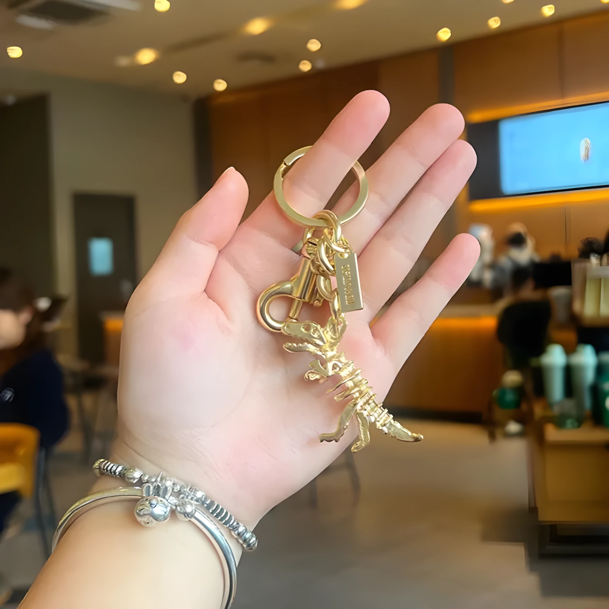 Zinc alloy dinosaur keychain with golden bone dragon pattern on grey background