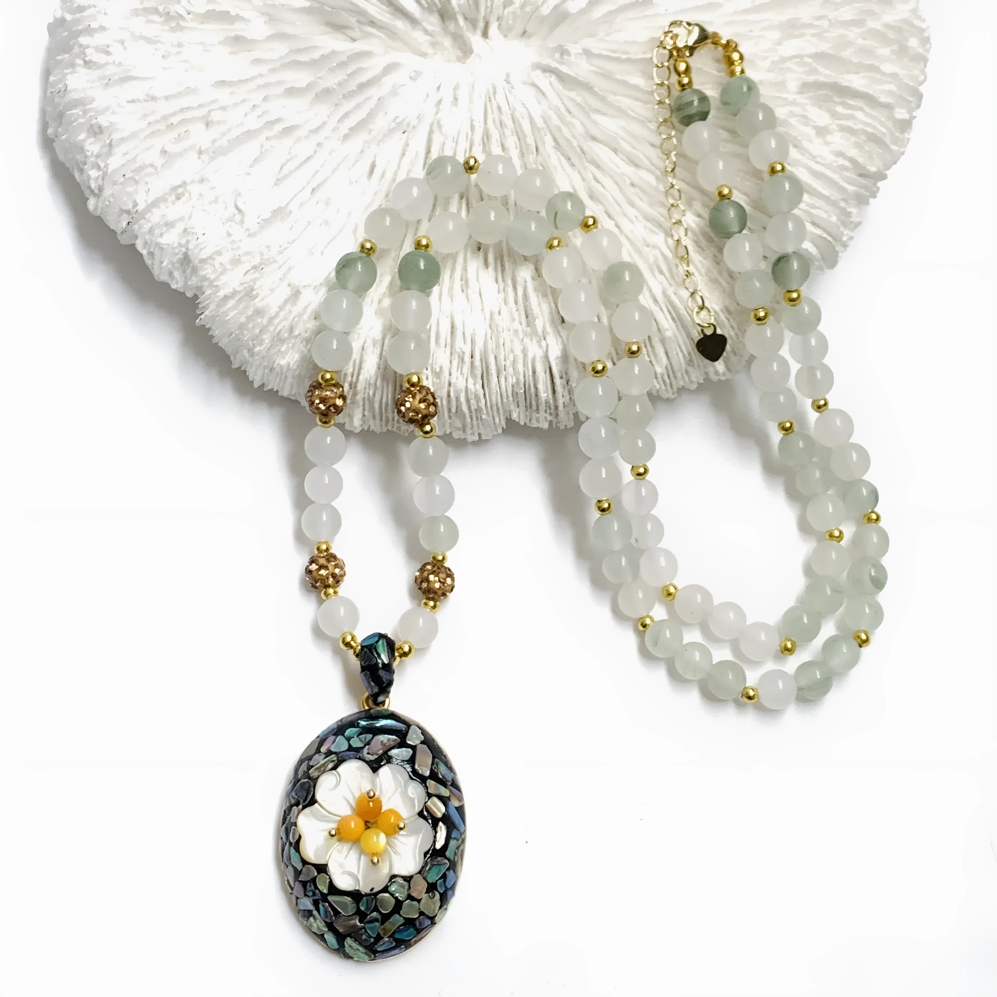 Original design mother-of-pearl lacquer shell necklace with rhinestone twist chain on display