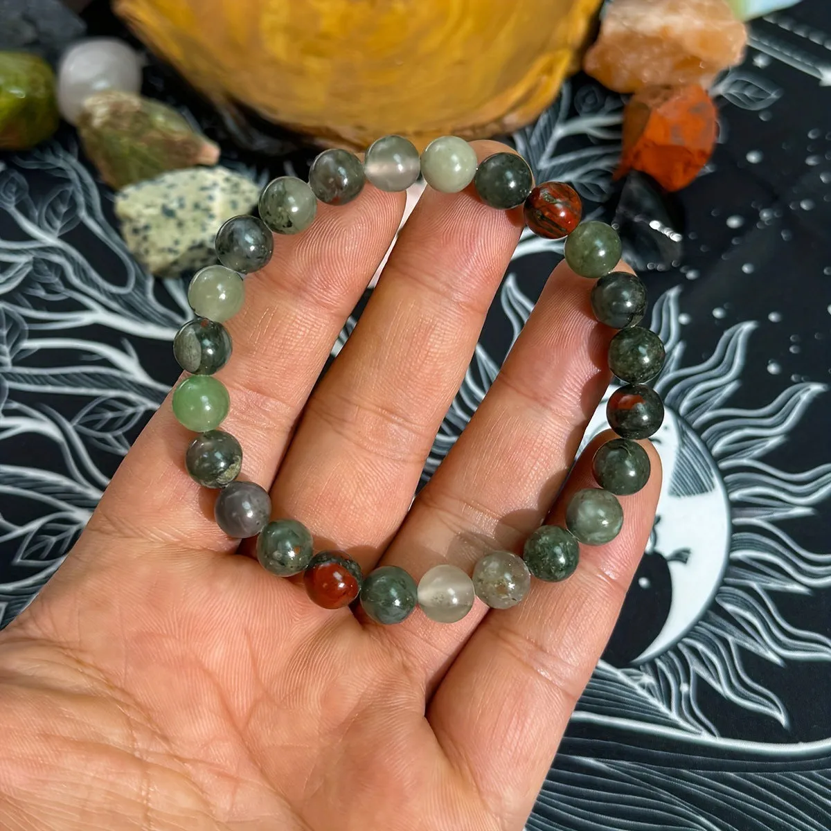 Handmade African Bloodstone beaded bracelet with 8mm transparent glass beads on neutral background