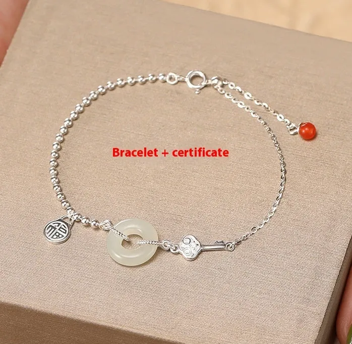 Women's Chinese style silver bracelet with a Hetian jade stone and intricate Peace Buckle design.