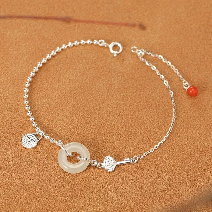 Women's Chinese style silver bracelet with a Hetian jade stone and intricate Peace Buckle design.