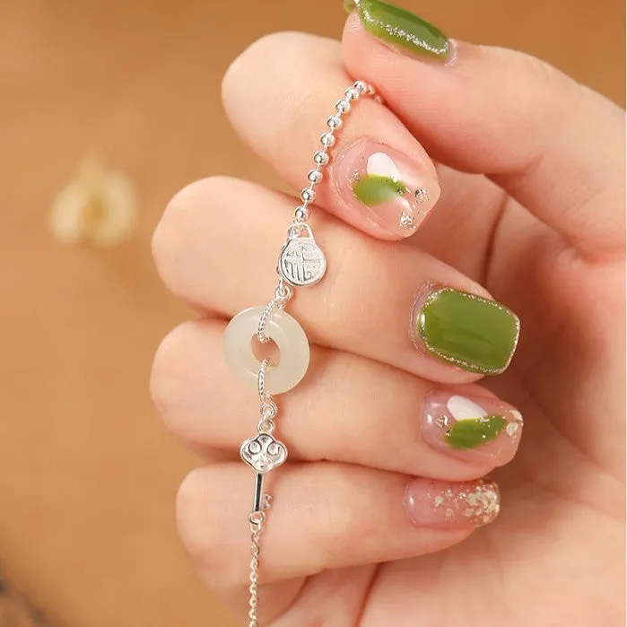 Women's Chinese style silver bracelet with a Hetian jade stone and intricate Peace Buckle design.