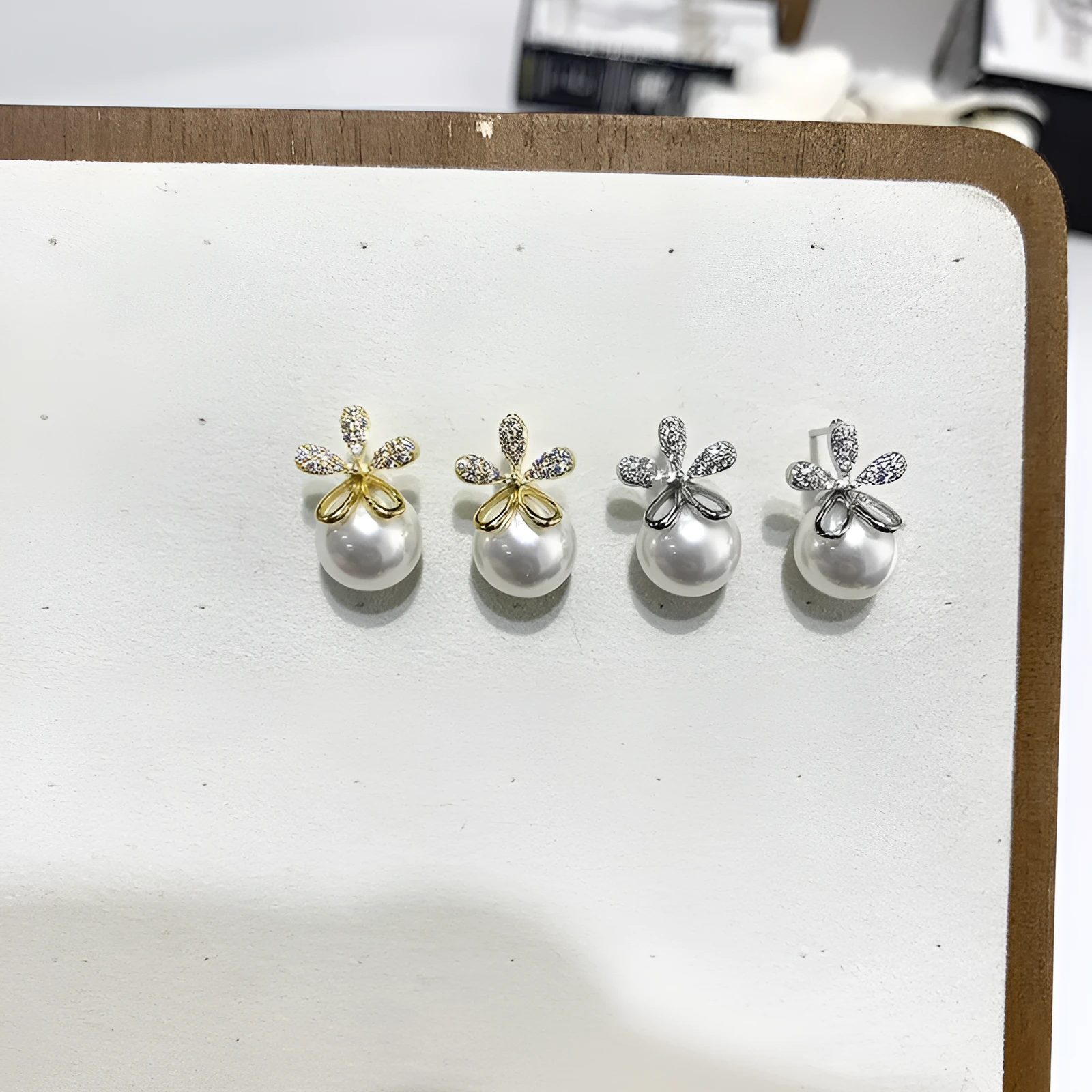 Pair of pearl flower drop earrings in gold and silver finishes on a light background