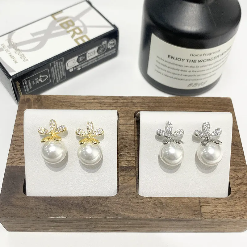 Pair of pearl flower drop earrings in gold and silver finishes on a light background