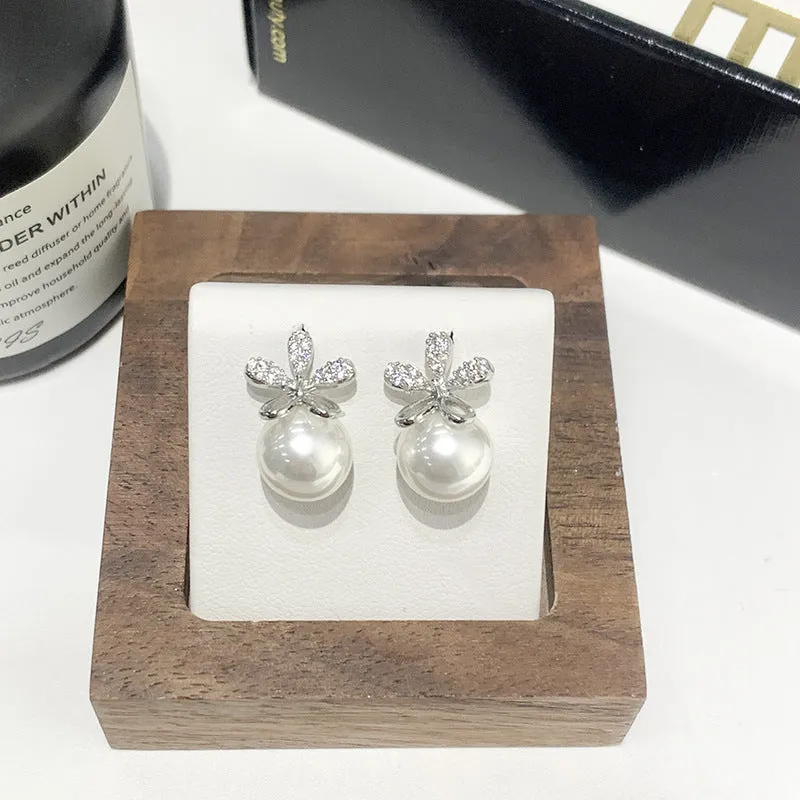 Pair of pearl flower drop earrings in gold and silver finishes on a light background