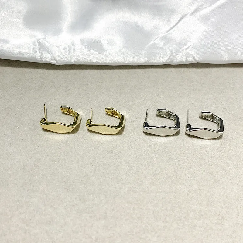 Irregular C-shaped metal stud earrings in Gold finish, minimalist design for everyday wear.