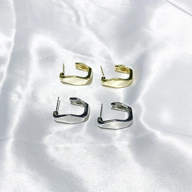 Irregular C-shaped metal stud earrings in Gold finish, minimalist design for everyday wear.