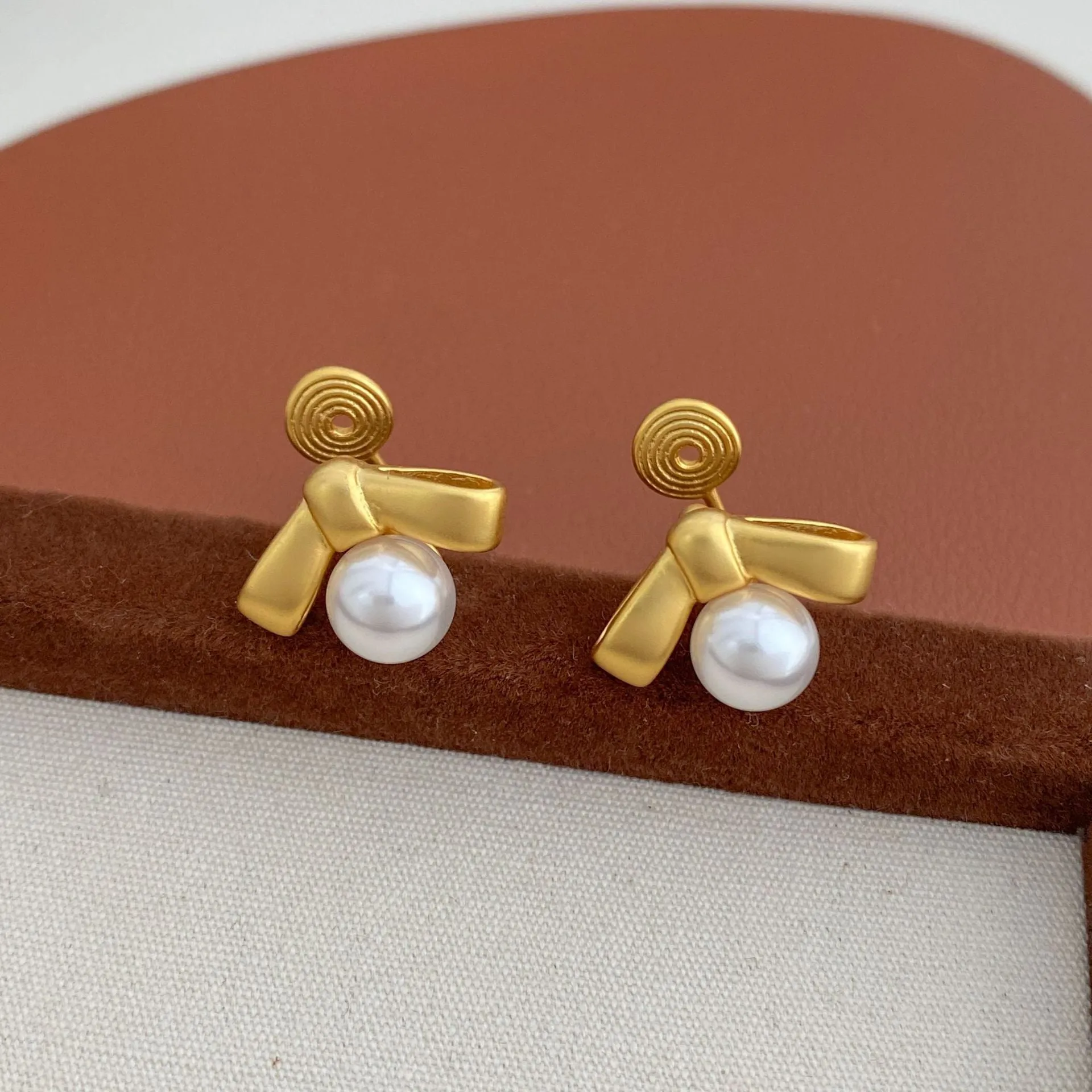 Matte bow earrings for women in matte gold clip-on style on a white background