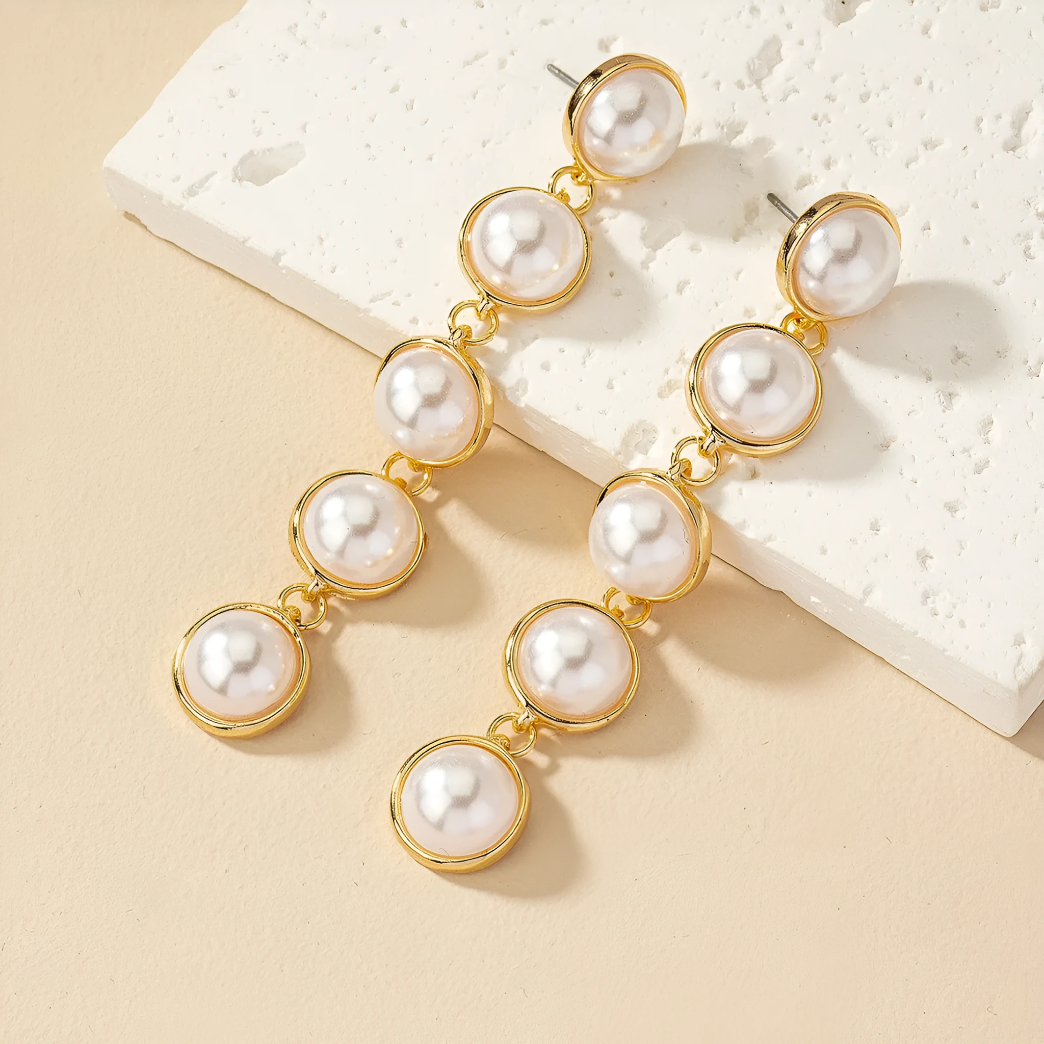 White metal drop tassel earrings with pearl water flow design on display