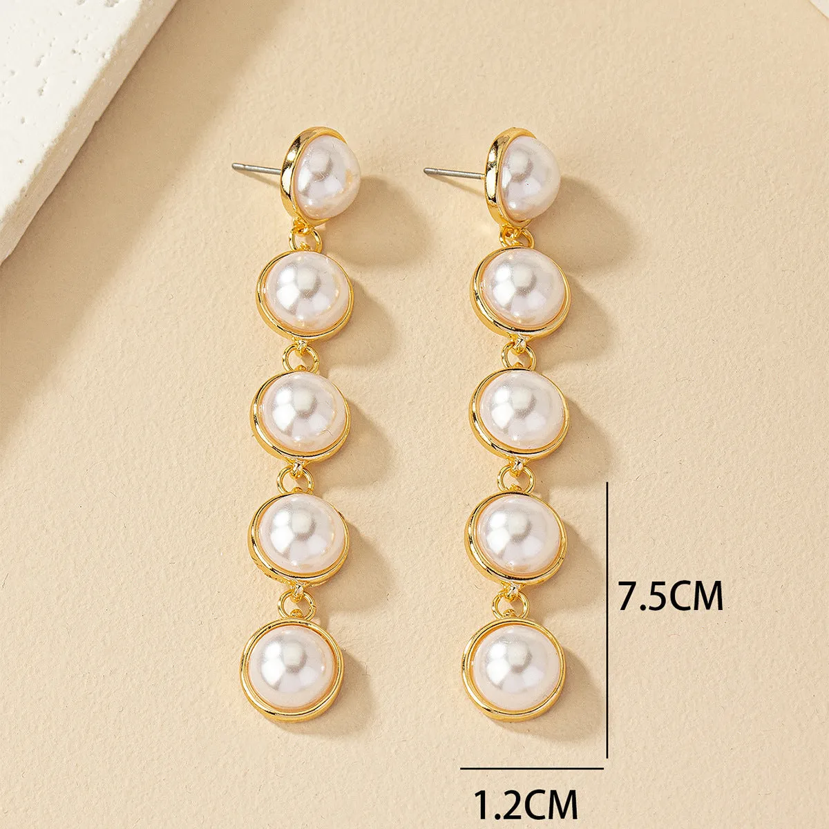 White metal drop tassel earrings with pearl water flow design on display