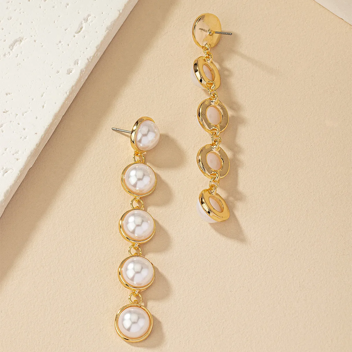 White metal drop tassel earrings with pearl water flow design on display