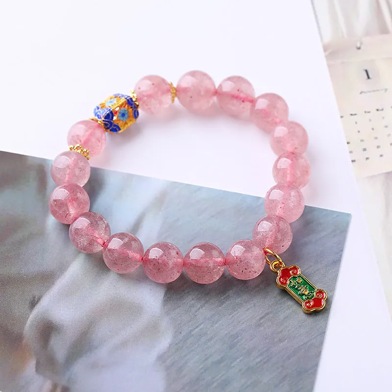 Close-up of a pink crystal bracelet with a Ruyi charm and text detailing on a woven chain.