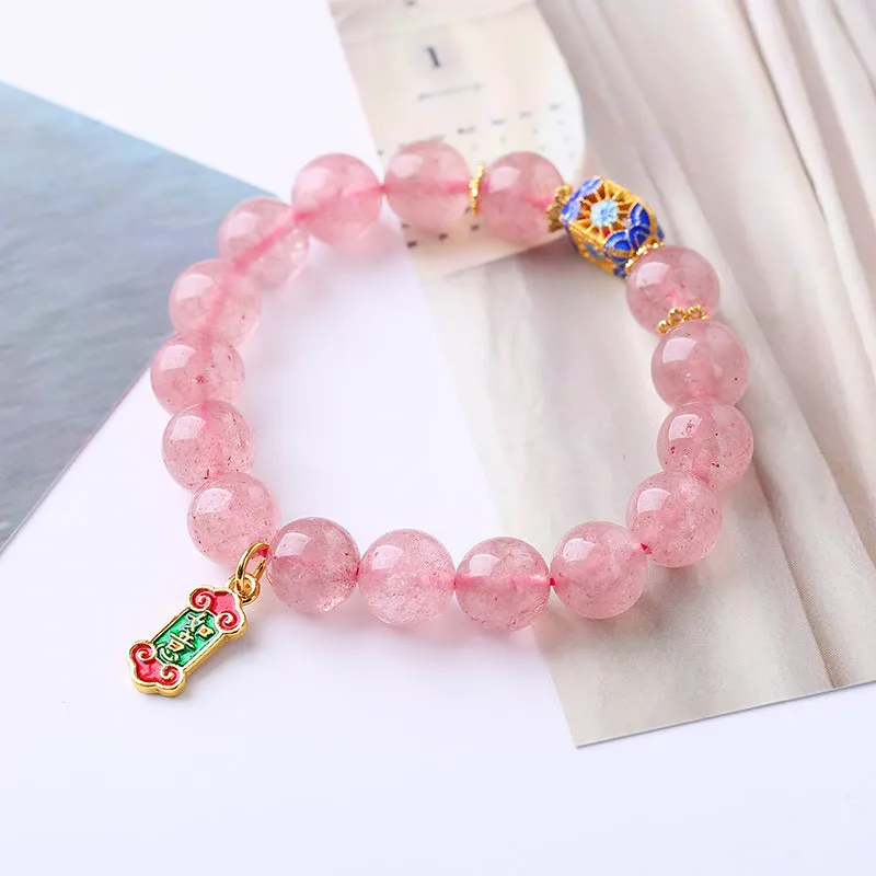 Close-up of a pink crystal bracelet with a Ruyi charm and text detailing on a woven chain.