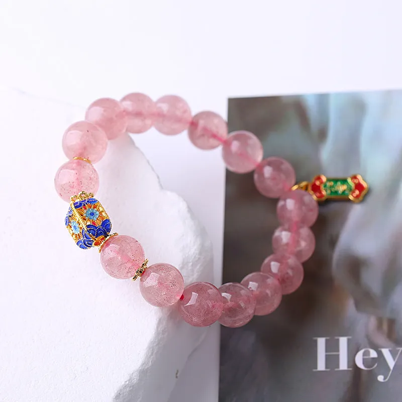 Close-up of a pink crystal bracelet with a Ruyi charm and text detailing on a woven chain.