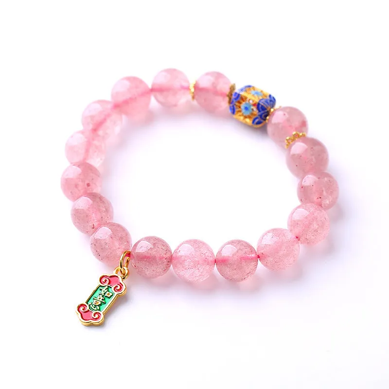 Close-up of a pink crystal bracelet with a Ruyi charm and text detailing on a woven chain.