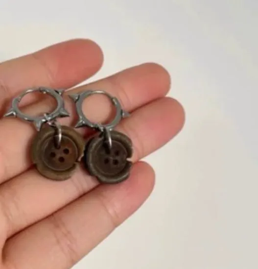 One pair of brown alloy ancient style burned gap button distressed earrings on neutral background