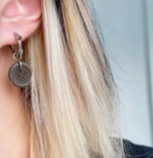 One pair of brown alloy ancient style burned gap button distressed earrings on neutral background
