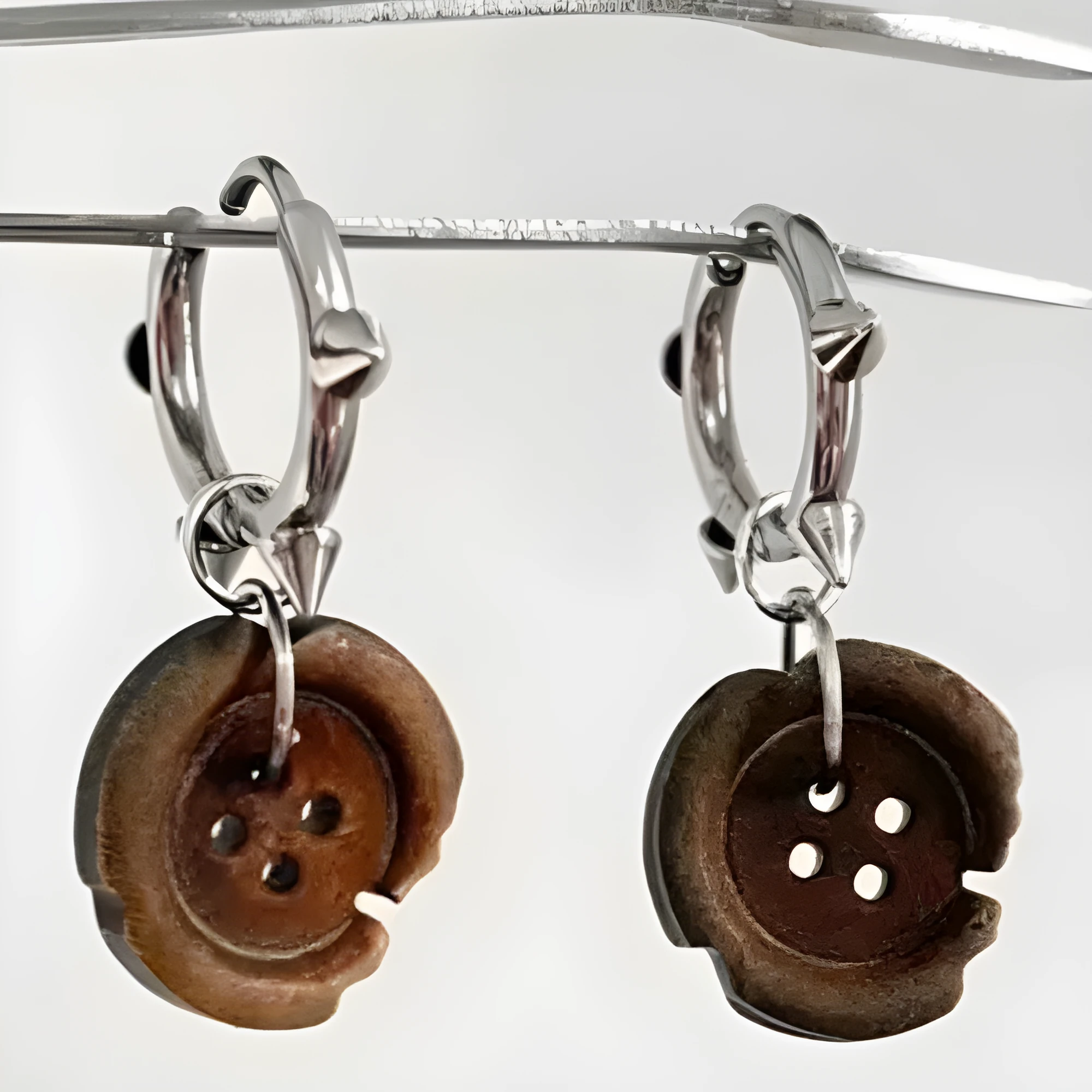 One pair of brown alloy ancient style burned gap button distressed earrings on neutral background