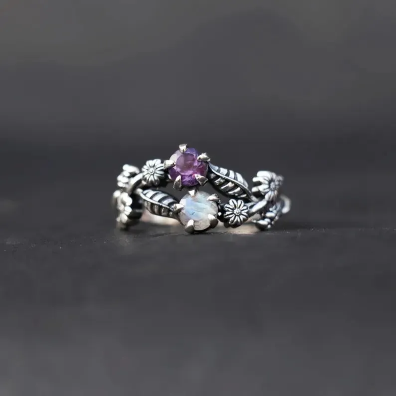 Silver zinc alloy flower ring with purple gemstone centre on light background