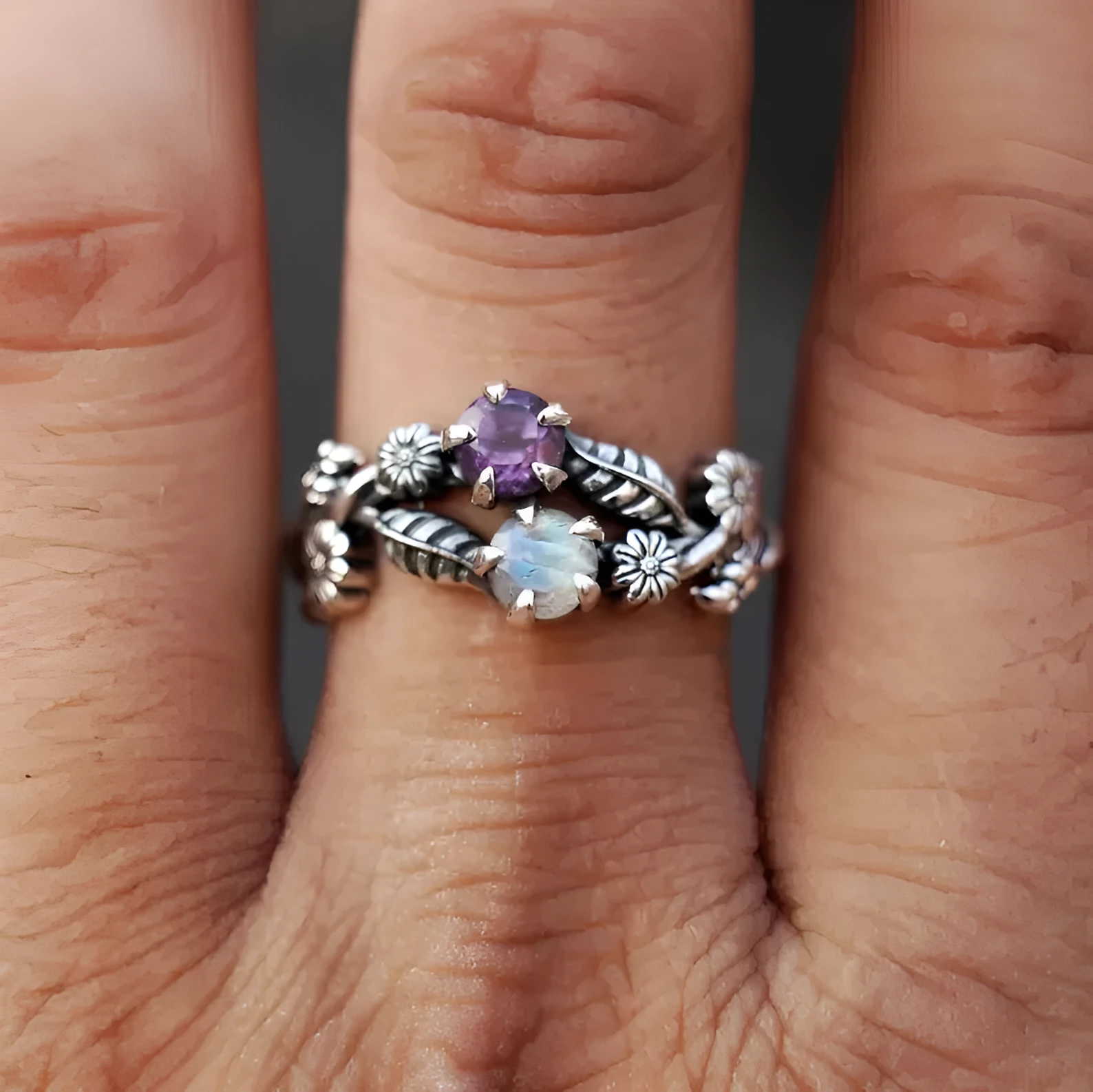 Silver zinc alloy flower ring with purple gemstone centre on light background