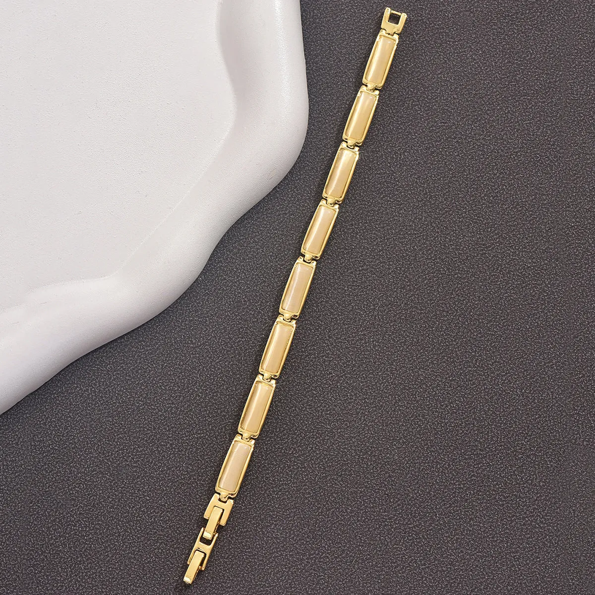 Women's geometric rose gold opal bracelet with quadrilateral shape and gemstone inlay on a plain background