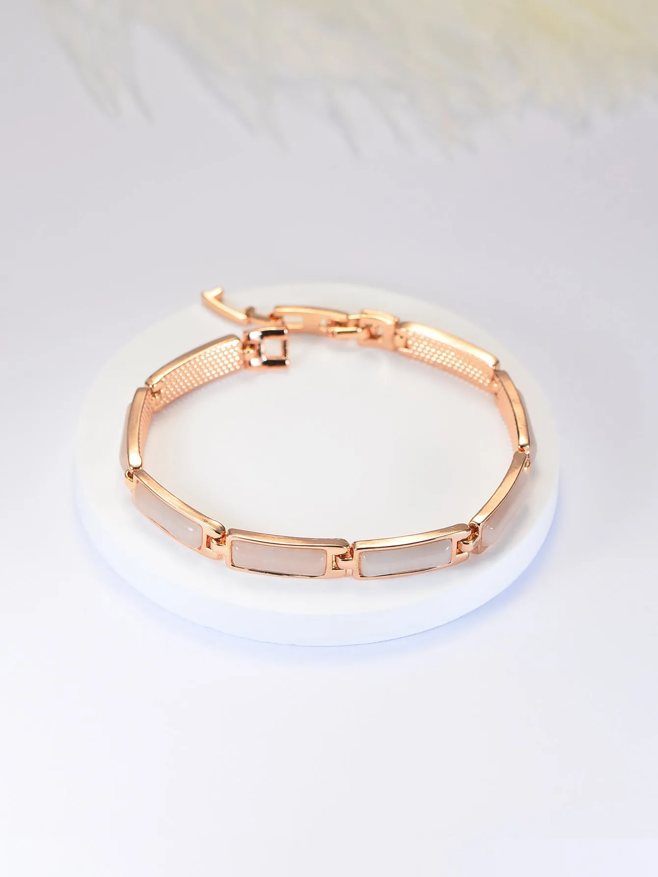 Women's geometric rose gold opal bracelet with quadrilateral shape and gemstone inlay on a plain background