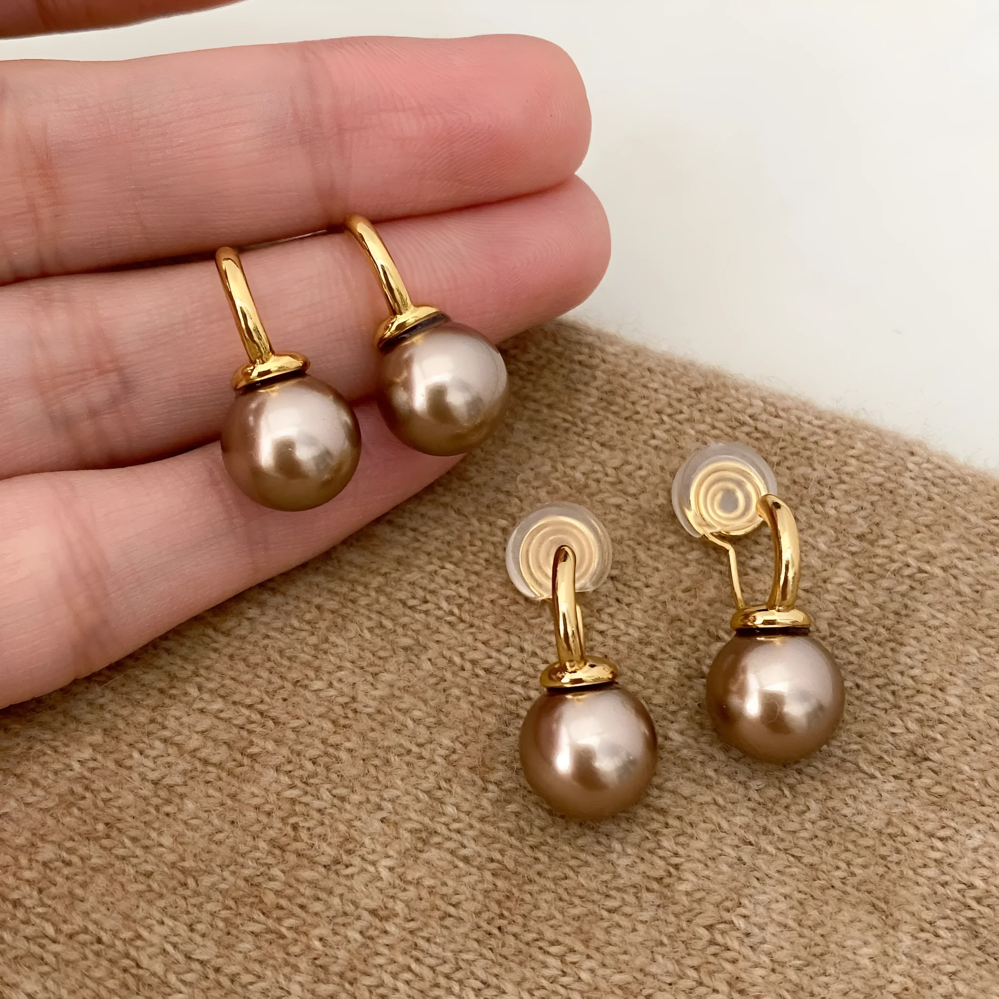 Vintage champagne pearl clip-on earrings with copper electroplated geometric design, on display as a pair