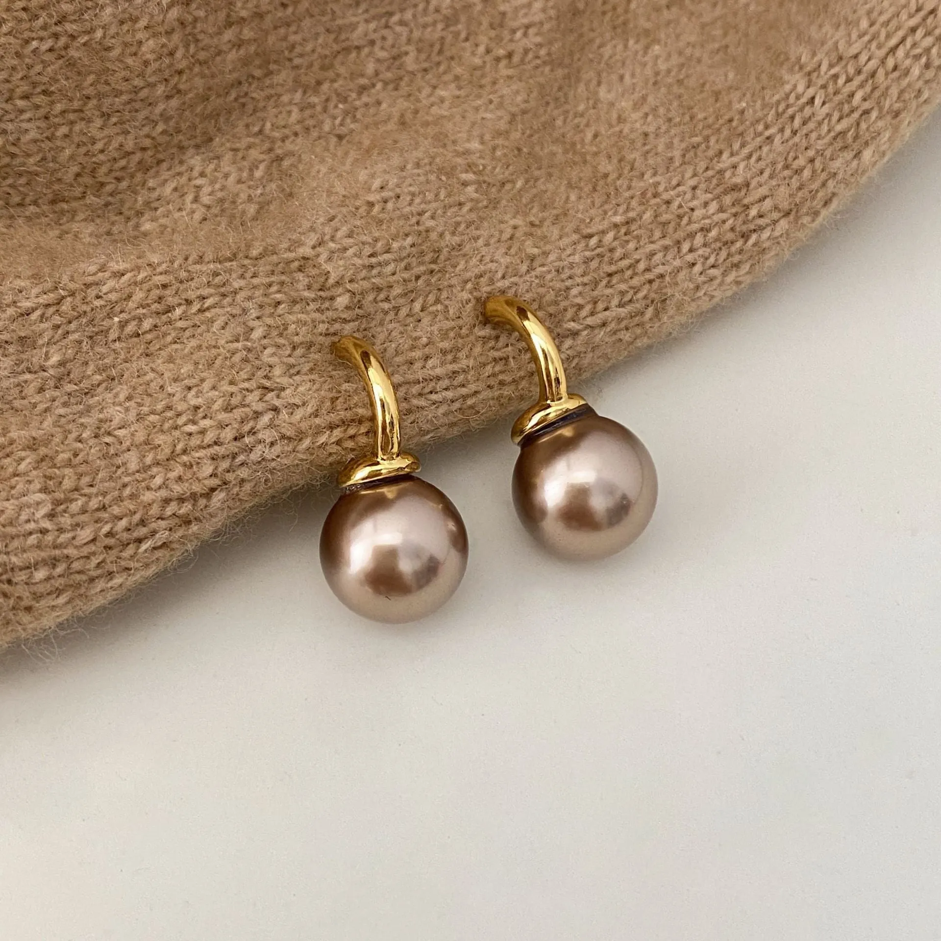 Vintage champagne pearl clip-on earrings with copper electroplated geometric design, on display as a pair