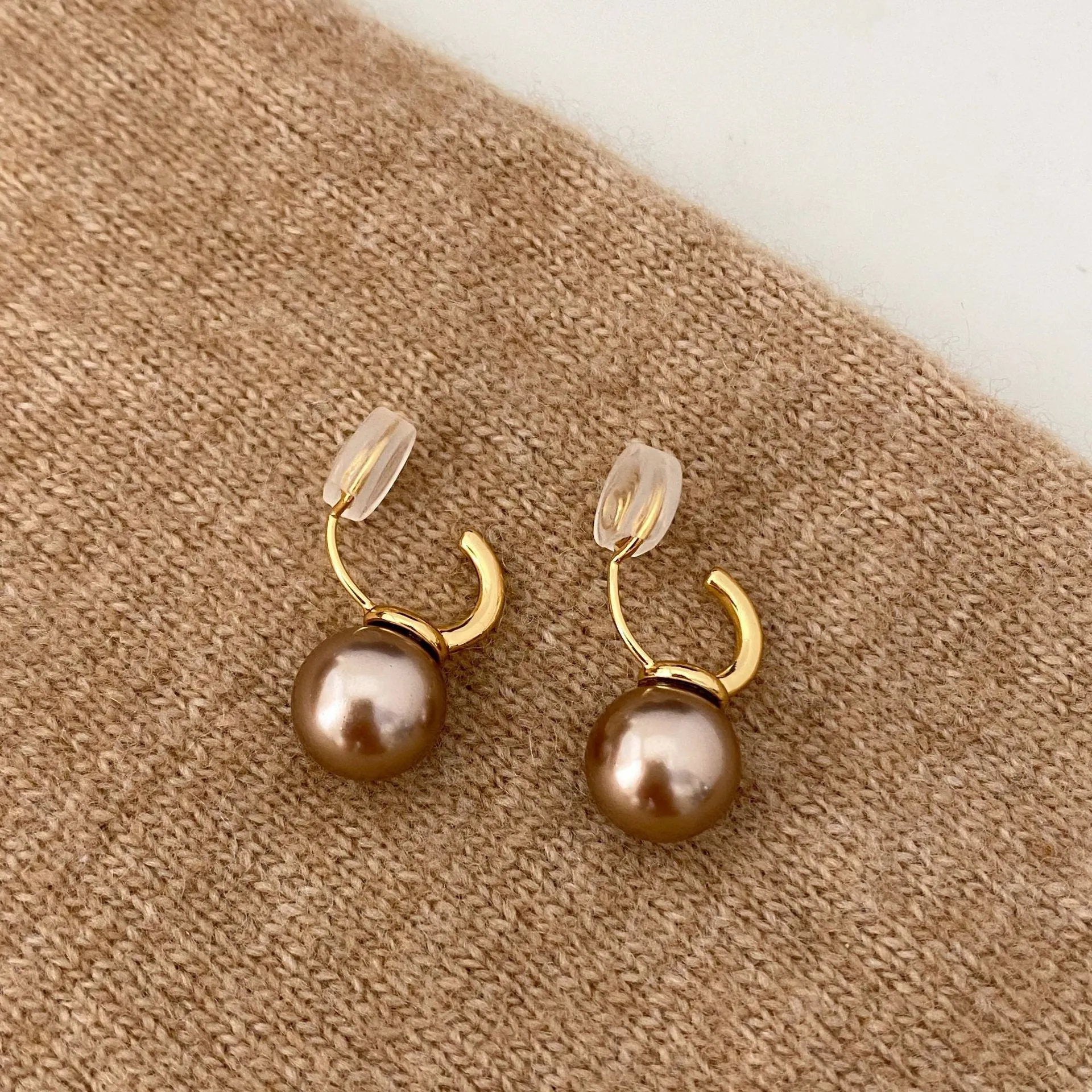 Vintage champagne pearl clip-on earrings with copper electroplated geometric design, on display as a pair