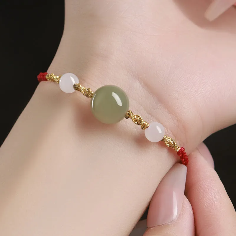 Hand-woven red rope bracelet with Hetian jade beads and intricate charm detailing.