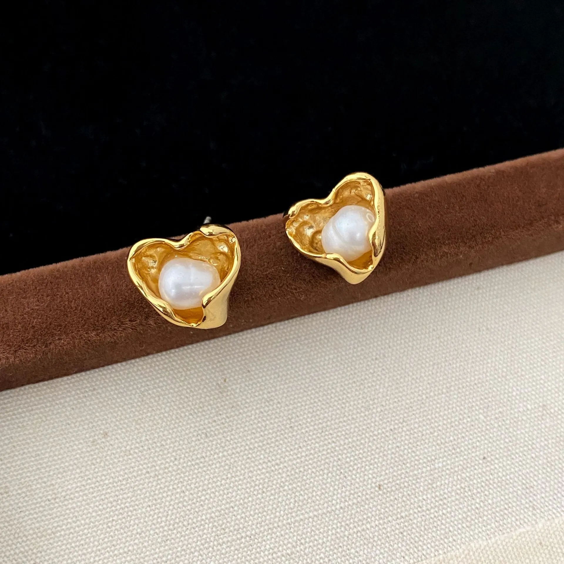 Pair of copper heart shaped irregular pearl earrings with electroplating finish on white background