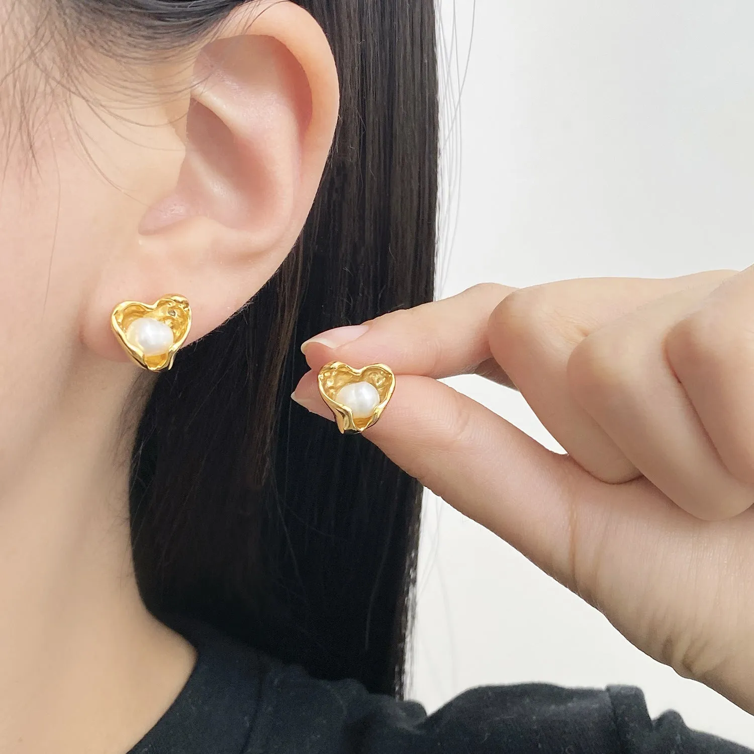 Pair of copper heart shaped irregular pearl earrings with electroplating finish on white background