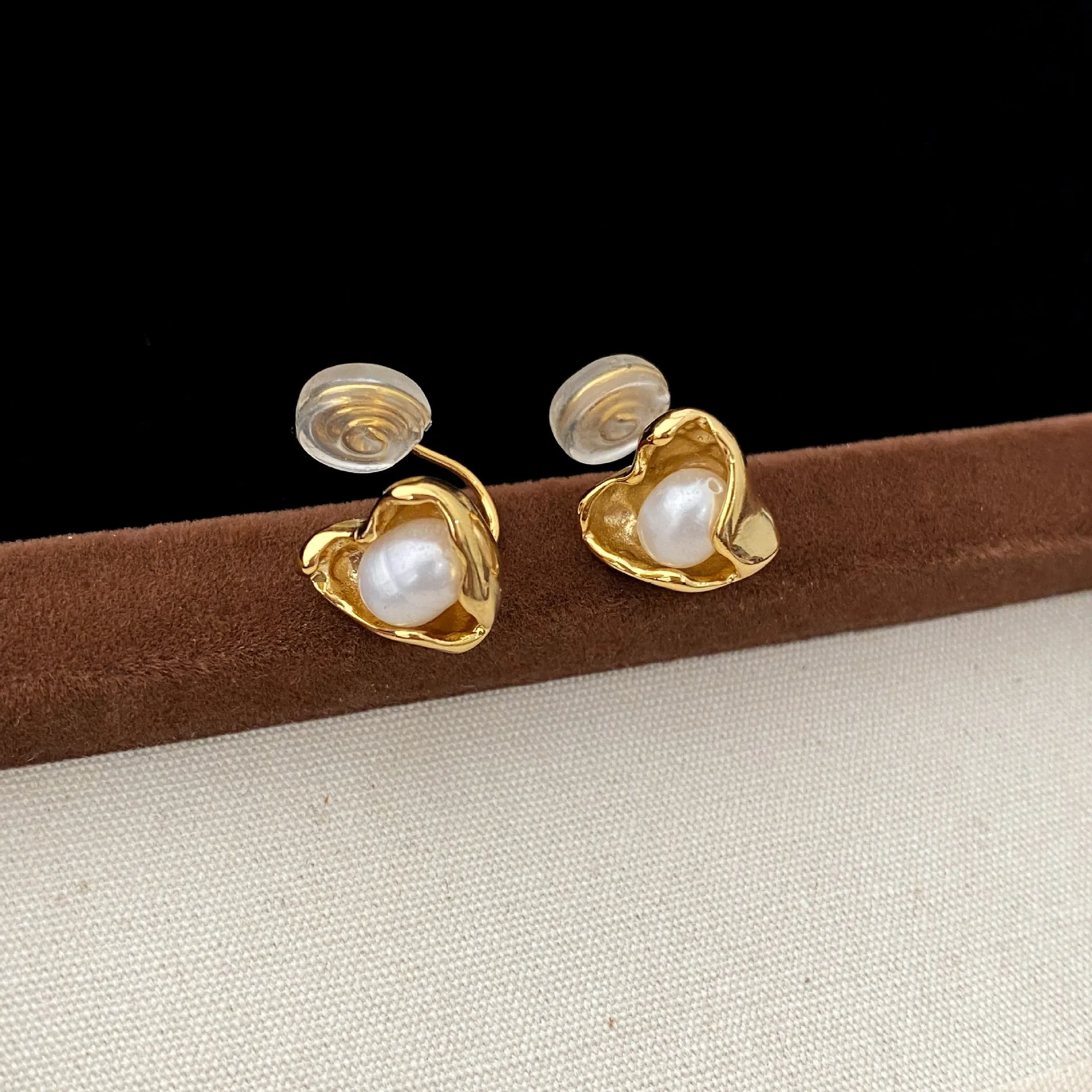 Pair of copper heart shaped irregular pearl earrings with electroplating finish on white background