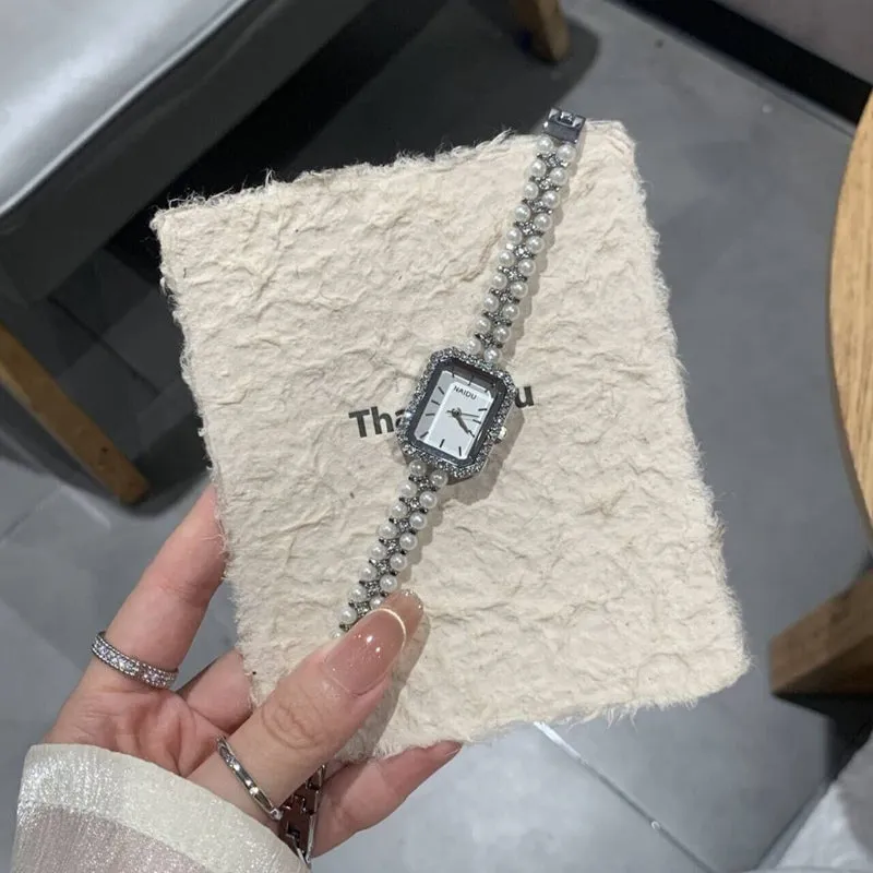 Women's fashion pearl bracelet watch with 30mm round dial, alloy strap, and quartz movement on white background