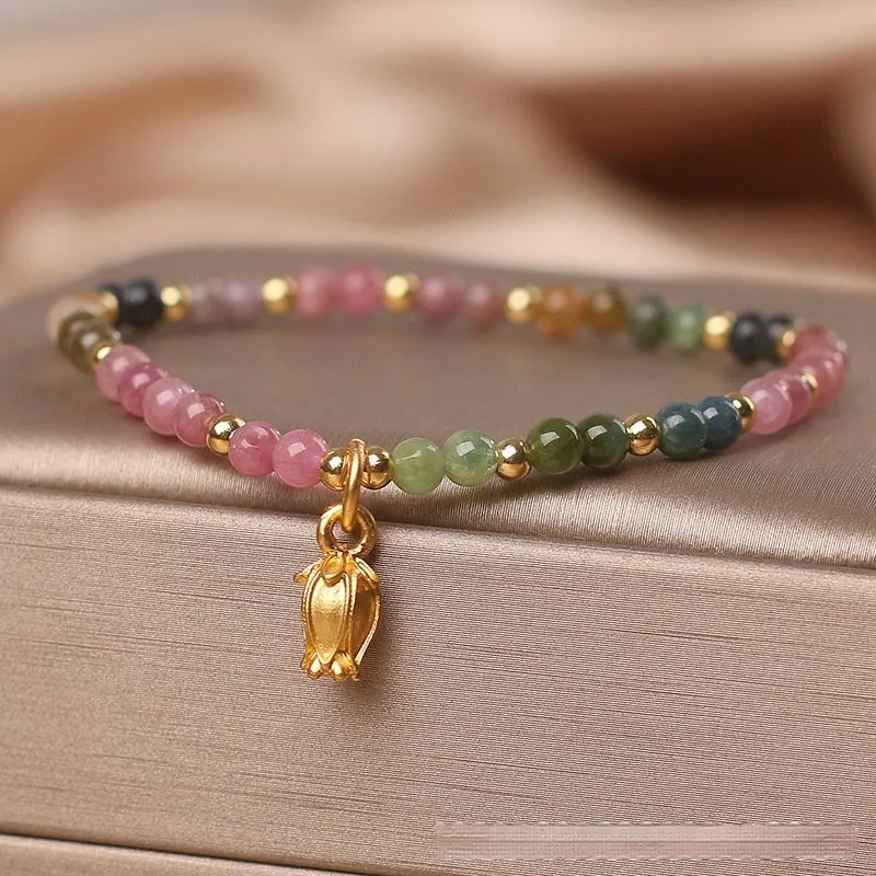 Natural tourmaline bead anklet for women with a silver flower charm on an ankle.