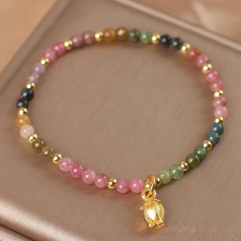 Natural tourmaline bead anklet for women with a silver flower charm on an ankle.