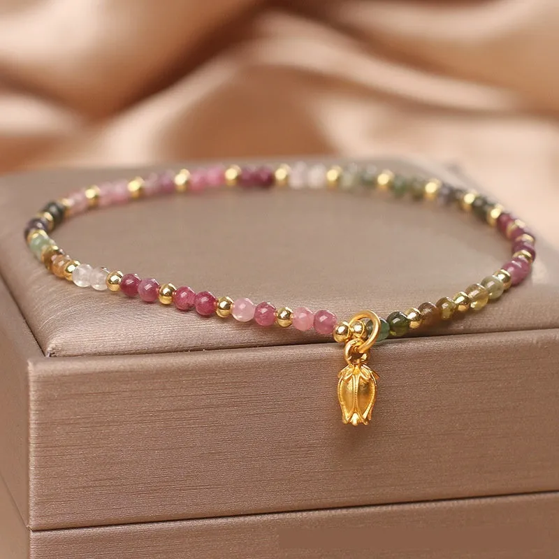 Natural tourmaline bead anklet for women with a silver flower charm on an ankle.