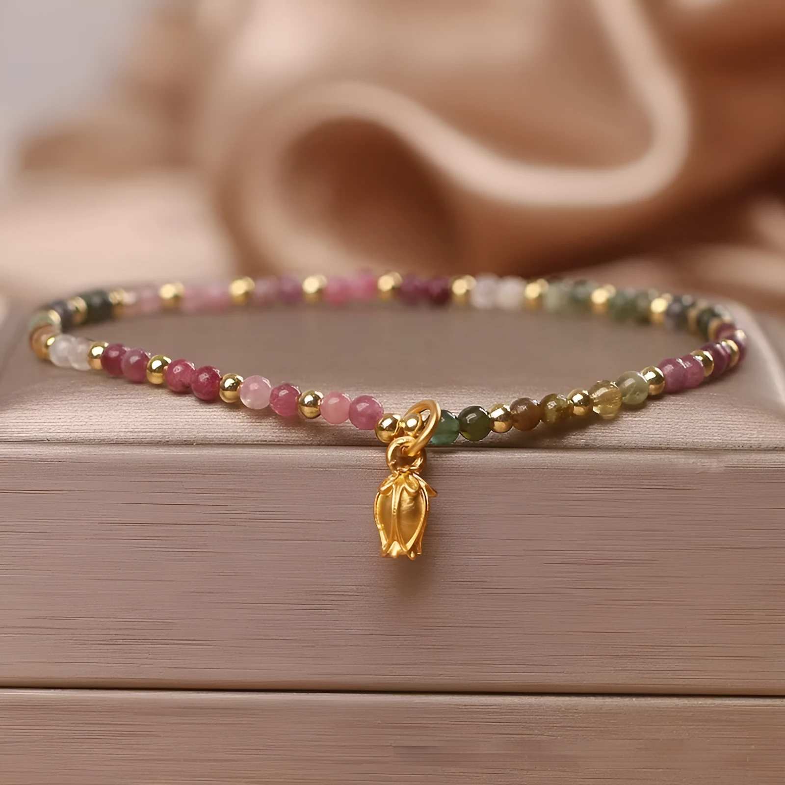 Natural tourmaline bead anklet for women with a silver flower charm on an ankle.