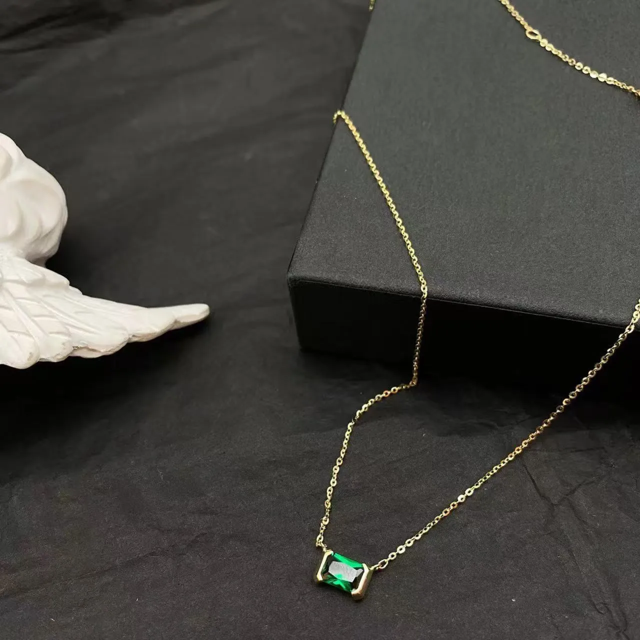 Women's gold geometric pendant necklace with quadrilateral design and inset cubic zirconia stones on chain
