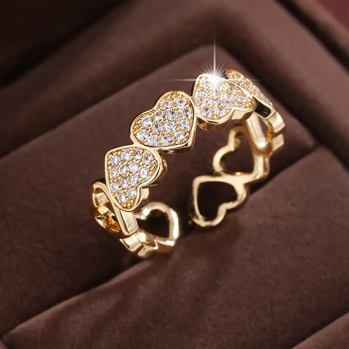 Gold copper couple ring with adjustable opening and love heart design on plain background