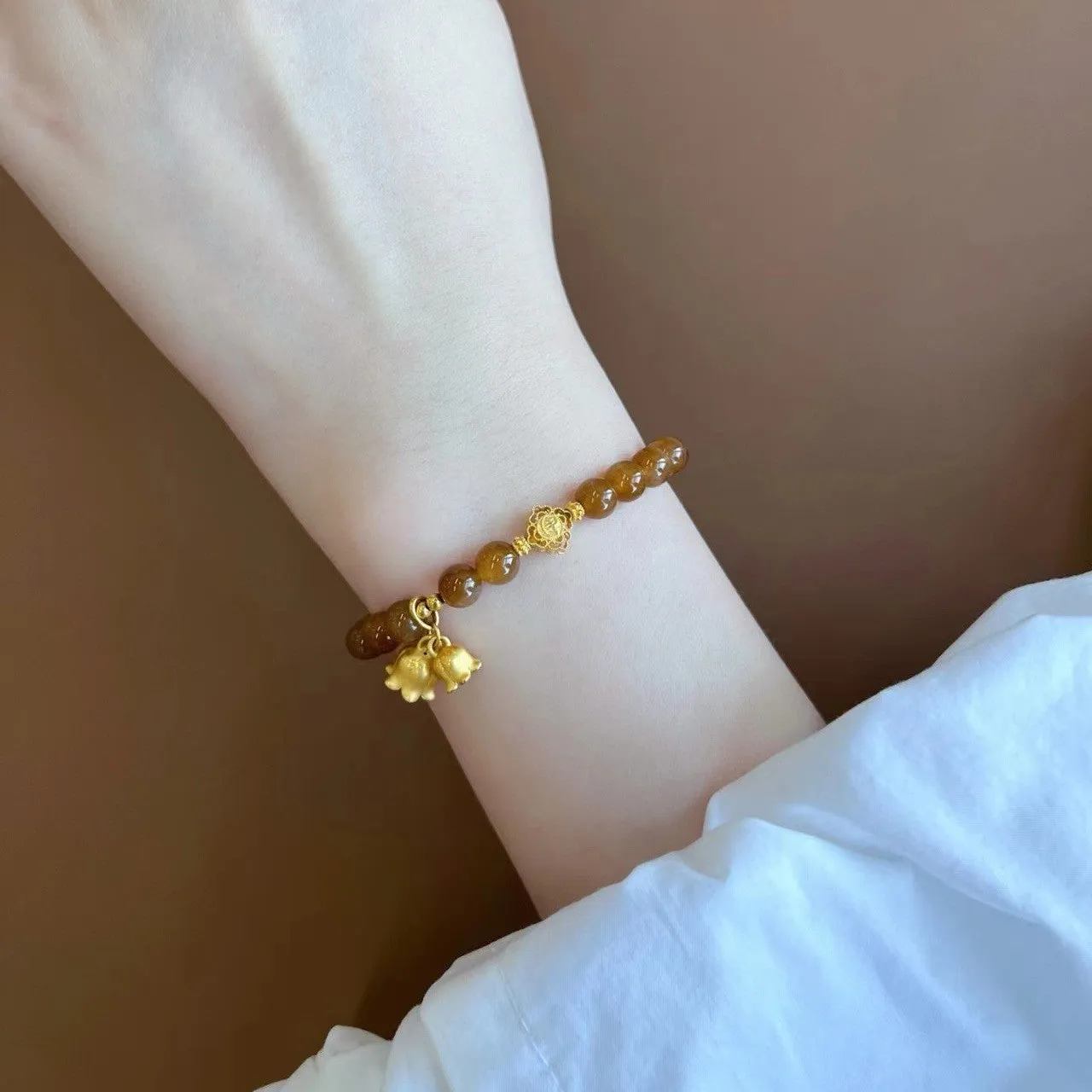 Caramel-coloured women's bracelet with electroplated beeswax finish and lily flower design.