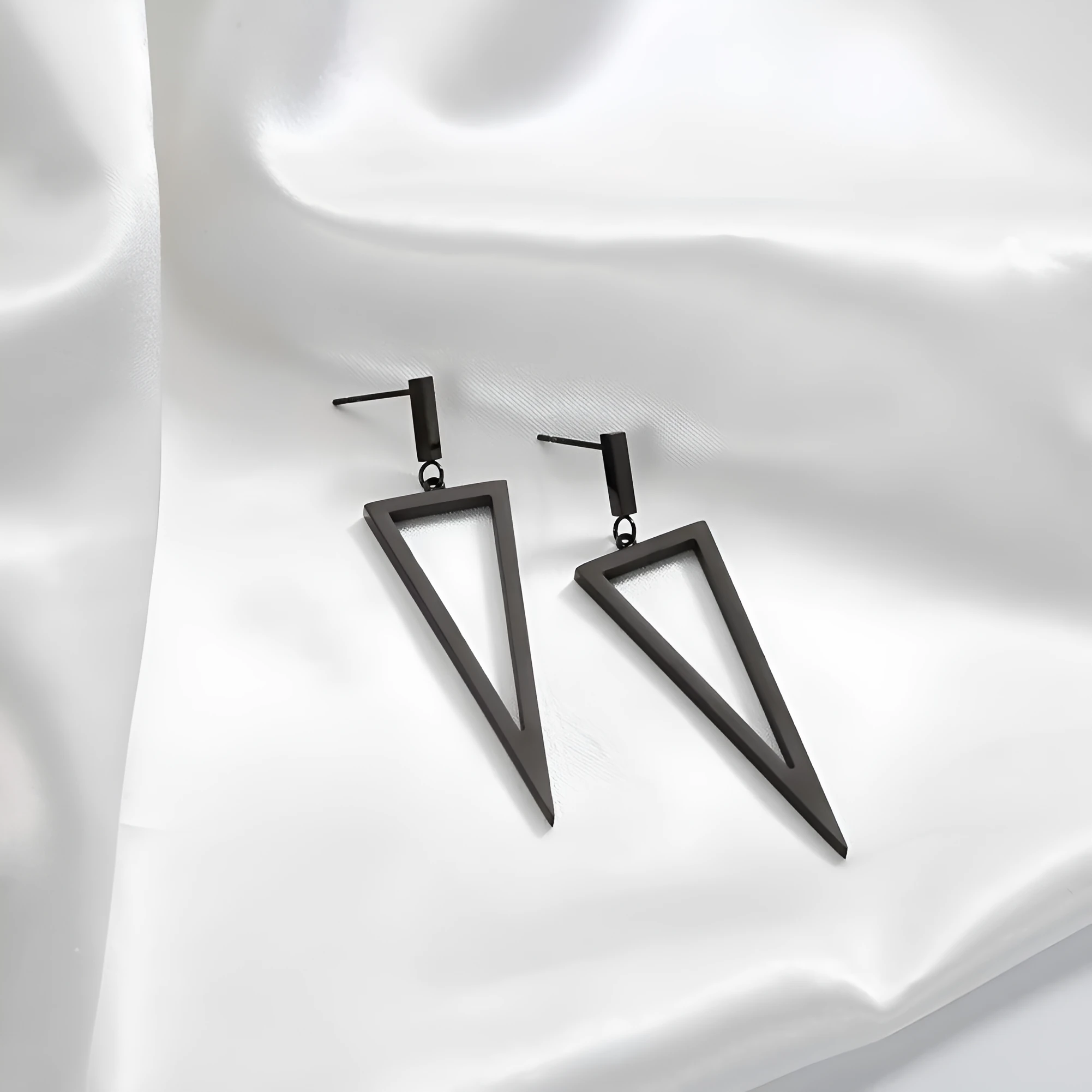 Black metal triangle earrings with electroplated finish on a plain background