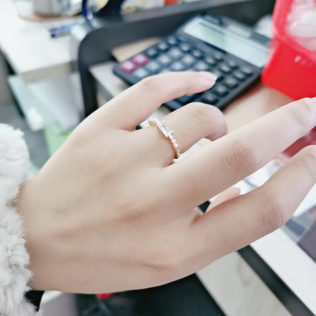 Gold alloy ring with square artificial gemstone inlay and diamond-cut surface, adjustable opening, on a white background