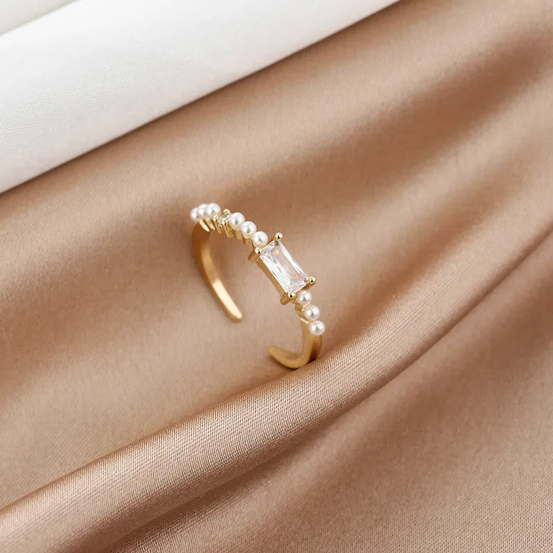 Gold alloy ring with square artificial gemstone inlay and diamond-cut surface, adjustable opening, on a white background