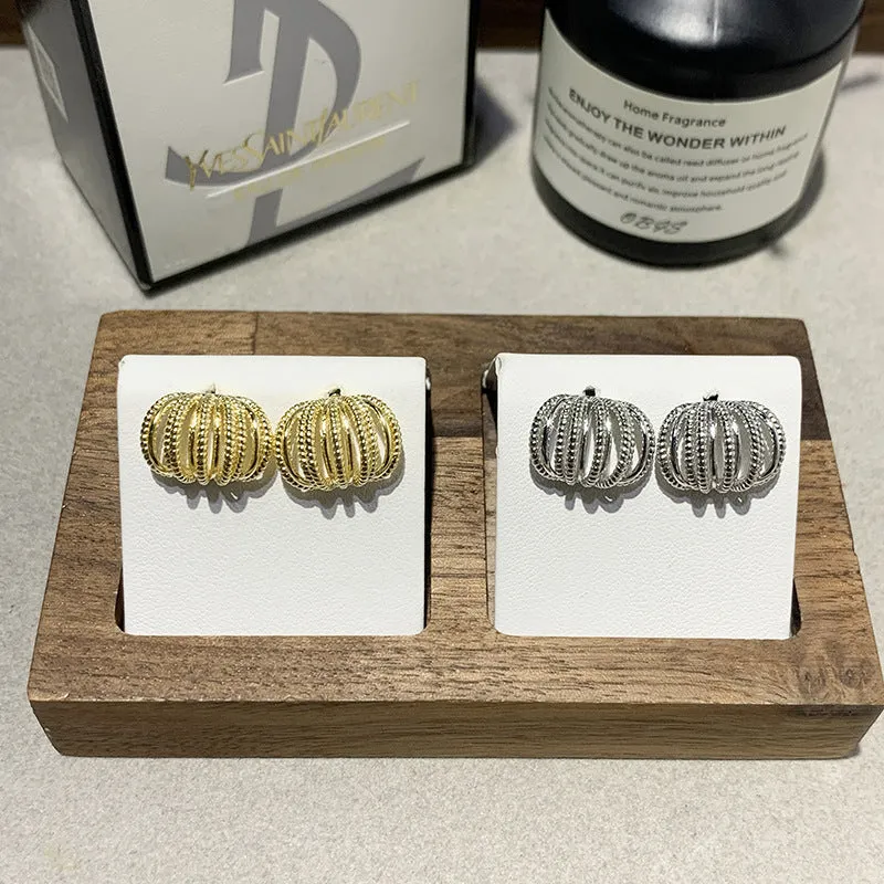 Multi layer metal wire C-ring earrings in gold and silvery colours on a neutral background