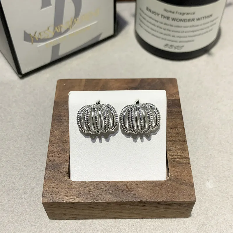 Multi layer metal wire C-ring earrings in gold and silvery colours on a neutral background