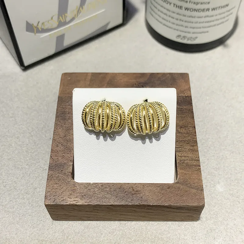 Multi layer metal wire C-ring earrings in gold and silvery colours on a neutral background