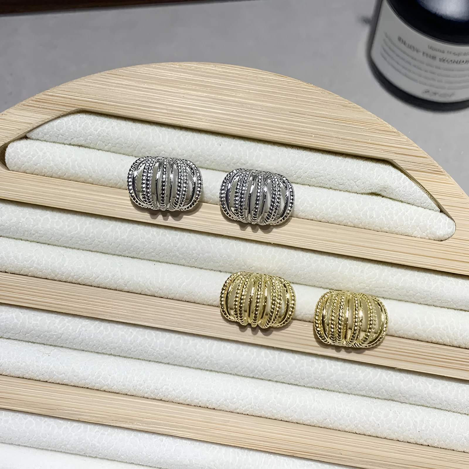 Multi layer metal wire C-ring earrings in gold and silvery colours on a neutral background