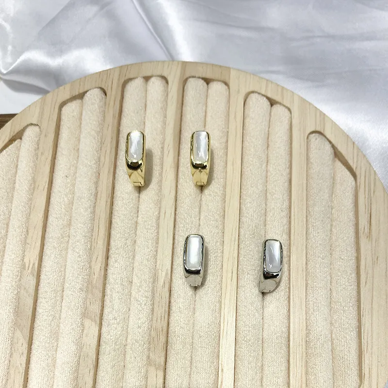 Four pairs of round buckle earrings in gold and silver metal finish on white background
