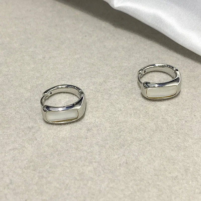 Four pairs of round buckle earrings in gold and silver metal finish on white background